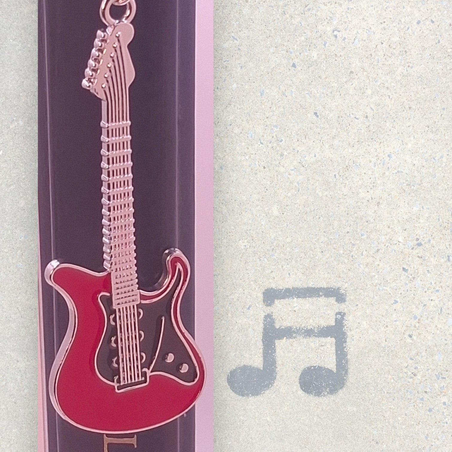 Red and black electric guitar on a floral-patterned bookmark on a gray background