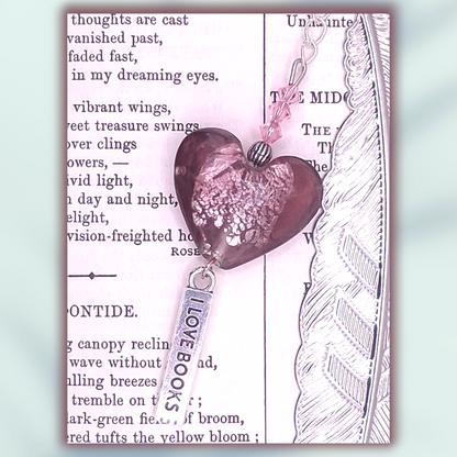 Silver-tone bookmark with accented with pink bicones and plum heart-shaped charm with rose iridescent crackling in the center, and with 'I Love Books' charm on a decorative background with text.